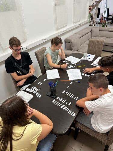 PO tábor 2024 - Logisztikai társasjáték, öt diák és a csoportvezető ül egy asztalnál