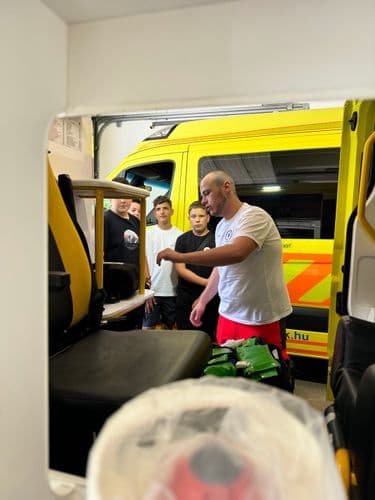 PO tábor 2024 - Mentőállomáson egy mentős magyaráz a mentőautóknál a tanulóknak