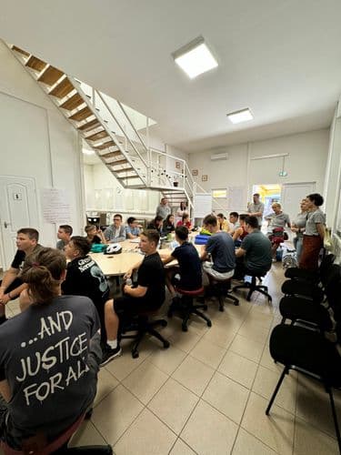 PO tábor 2024- tanulók a DKA aulájában ülnek az ovális asztalnál, háttérben a konyha és az emeletre vezető lépcső